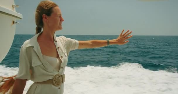 海の広がりにあるボートに乗ったジョイフルな女性 観光ガールは地平線に向かって手を伸ばし 暖かさと広大な開いた水を感じる — ストック動画