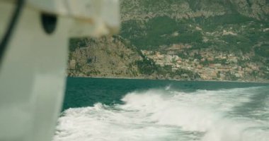 Arka planda tepeler ve ön planda deniz dalgaları olan bir tekneden Positano kıyı kasabasının görüntüsü. İtalya 'ya yaz gezisi..