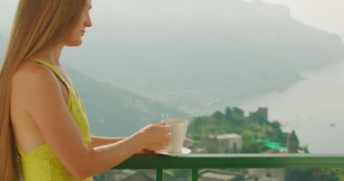 Bir kadının manzaralı bir dağ zeminiyle ılık içkisinin tadını çıkardığı huzurlu bir an. Huzurlu atmosfer, onun sessiz yansımasının zevkini arttırır...