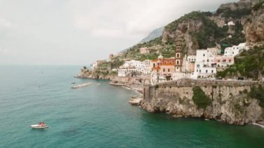 Atrani kasabasının sahil şeridi, uçurum kenarındaki evler ve denizde tekneler. İtalya 'da yaz tatili..