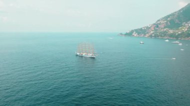 Amalfi Sahili yakınlarındaki açık denizde uzun bir yelkenli gemi. Uzak karaları ve görünen tekneleri var...