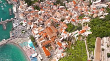 Sahil kenti Amalfi 'nin renkli şemsiyeler, tarihi bir bölge ve açık mavi sularda demirlemiş teknelerle dolu yoğun bir plajı var. Yaz İtalya..