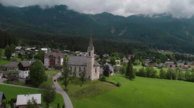 Bulutlu bir günde, Avusturya 'nın Gosau kentindeki evleri ve dağları çevreleyen kilisenin hava manzarası