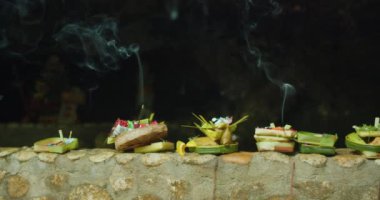 Hindu ruhlarına adaklar sunan tabakların yakın görüntüsü ve açık havada yanan aroma çubuğu. Bali Nusa Penida 'daki Endonezya kültürü. Aromatik tütsü dumanı ve çiçek yaprakları Tanrı 'ya getirildi..