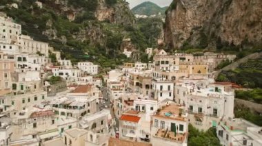 Dağlarla çevrili Atrani şehrinin caddelerinin ve evlerinin havadan görünüşü. İtalya 'da yaz tatilinde gezmek..