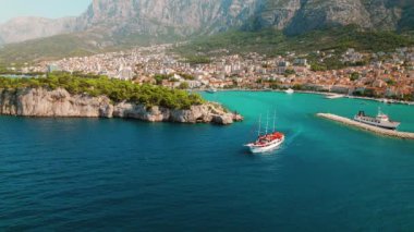 Yazın güneşli bir günde Makarska kasabası yakınlarındaki bir kayalıklarda bir yelkenli geziyor. Adriyatik Denizi ve kenti Hırvatistan 'da yoğun yerleşim yeri..