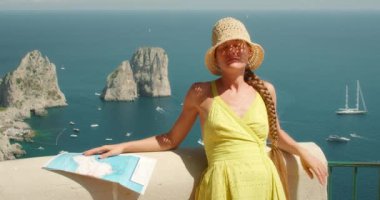 Capri Adası 'nın arka planında Faraglioni kaya oluşumlarıyla güneşlenen bir kadın...
