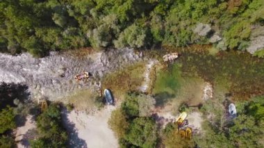 Çetina nehrinin berrak sularında, yazın güneşli bir günde Hırvatistan 'ın yemyeşil sularıyla çevrili olarak dolaşan insan gruplarıyla dolu botlar görülüyor...