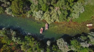 Hırvatistan 'da yaz aylarında Cetina nehrinde düzenlenen rafting yarışının hava görüntüsünde, suda yüzen katılımcıların yer aldığı birden fazla sal görülüyor. Yoğun yeşil orman..