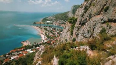 Omis 'in kıyı kasabası, arka planda dağlar bulunan açık mavi gökyüzünün altında bir dağ ve deniz arasında kurulmuştur. Yaz Hırvatistan..