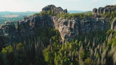 Yoğun bir ormanın kenarlarından yükselen sarp kayalıklar, etrafındaki sakin vadiyle çelişiyor. Almanya 'da Schrammsteine Coğrafi Özelliği..