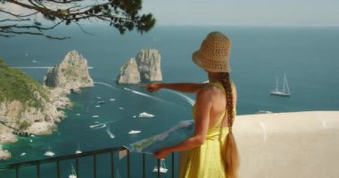 Capri İtalya 'da elinde bir haritayla Faraglioni kaya oluşumlarını gösteren bir kadın..