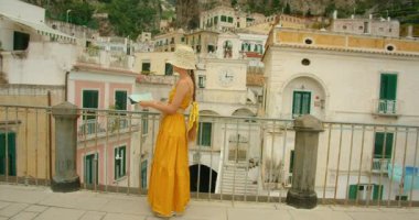 İtalya 'nın Atrani şehrinde haritalı, renkli binalar ve saat kulesiyle gezen bir kadın..