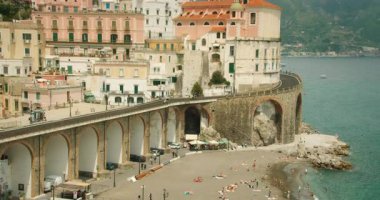 İtalya 'nın Atrani şehrindeki kumsalda renkli evler ve kemerli köprü..