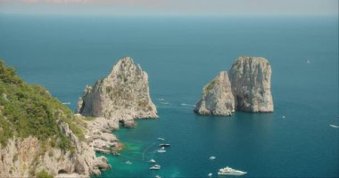 Capri İtalya 'sındaki Faraglioni kayalarını çevreleyen kayalıklar ve berrak mavi sular..