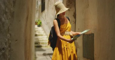 Sırt çantalı kadın İtalya 'nın Amalfi kasabasında dar bir geçidi keşfederken harita okuyor..