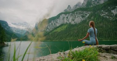 Bereketli yeşillik ve uçurumlarla çevrili sakin bir dağ gölünde meditasyon yapan kadının manzarası. Gosausee Avusturya..