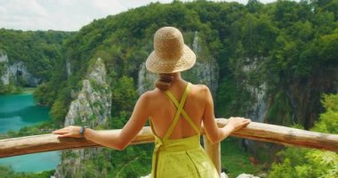 Genç kadın Plitvice Gölleri Ulusal Parkı 'nın orman kayalıklarına ve turkuaz suyuna hayran..