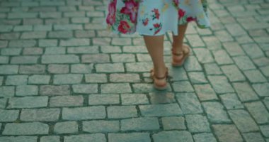 Prag 'da yaz akşamı kaldırım taşı caddesinde yürüyen sandaletli bir kadın..