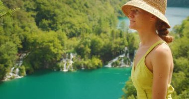 Plitvice Lakes Ulusal Parkı 'ndaki turkuaz göle ve şelalelere bakan kadın.