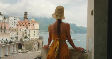 İtalya 'da yaz mevsiminde bir balkondan Atrani ve denize bakan bir kadın..