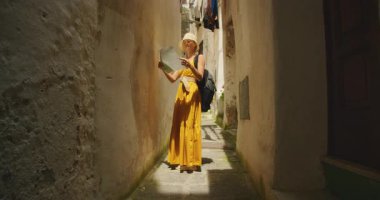 İtalya 'nın Amalfi kasabasında dar bir sokakta harita okuyan elbiseli bir turist kadın..
