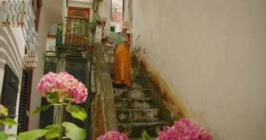 Elinde harita olan bir kadın İtalya 'nın Amalfi şehrinin çiçek sokağında taş merdivenlerden iniyor..