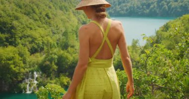 Hırvatistan 'daki Plitvice Gölleri Ulusal Parkı' ndaki yeşil vadi ve şelalelere hayran bir kadın kenarda yürüyor.