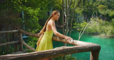 Plitvice Gölleri Ulusal Parkı 'ndaki yaz şelalesi ve göle hayran bir kadın.