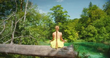Hırvatistan 'da yaz aylarında Plitvice Gölleri' nin turkuaz suyunun üzerinde meditasyon yapan kadın.