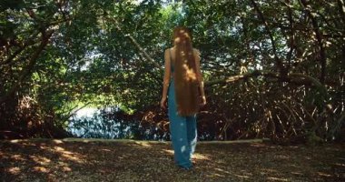 Çıplak ayaklı bir kadın Meksika 'da sık bir mangrov ormanının önünde tek başına yürüyor..