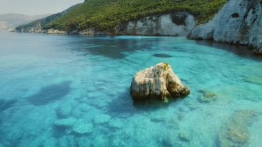 Yunanistan 'ın Kefalonia kentindeki beyaz kayalıkların yakınındaki açık turkuaz denizde büyük bir kaya bulunuyor.