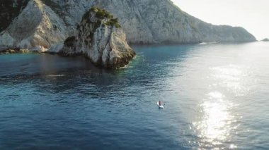 Yunanistan 'ın Kefalonya adasındaki dramatik kireçtaşı kayalıklarının yakınındaki sakin bir körfezde kano süren kişi.
