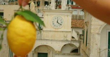 Yaz günü Amalfi 'de eski bir İtalyan saat kulesinin önünde elinde taze bir limon tutan bir kadın..