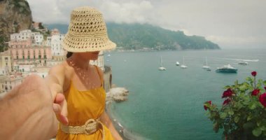 Kadın, Amalfi sahillerine ve yaz günlerinde teknelere bakarken erkeğin elini tutuyor..