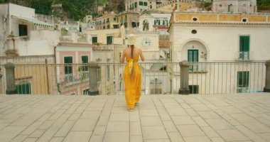 Yaz günü İtalya 'nın Amalfi Sahili' ndeki Atrani şehrinin saat kulesiyle şehir meydanına yaklaşan bir kadın..