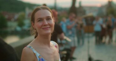 Prag 'da köprüde sokak bandosunun yanında dururken gülümseyen bir kadın..