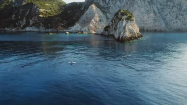 Paddleboardcu, Kefalonia kıyısındaki kayalıklarla çevrili el değmemiş koyları keşfediyor..