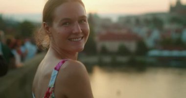 Prag 'da Charles Köprüsü' nde Vltava Nehri 'yle gülümseyen ve dans eden bir kadın ve alacakaranlıkta gökyüzü..