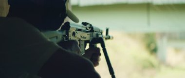 Tetikçi dürbünlü tüfekle nişan alıp ateş ediyor..