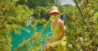 Hırvatistan 'daki Plitvice Gölleri Ulusal Parkı' nda şelaleli bir kadın turkuaz göl kenarında poz verdi.