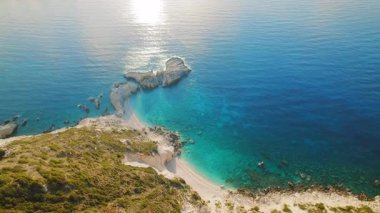 Kefalonya 'da turkuvaz suyu ve kayalık kayalıkları olan tenha sahil koyunda Yunanistan.