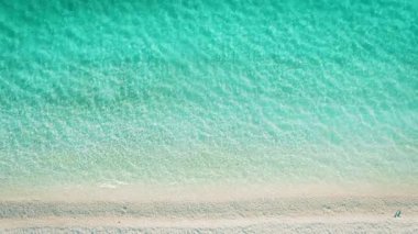 Turkuaz deniz suyunun güneşli yaz sabahında kumlu sahilde yıkandığı en iyi manzara..