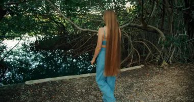 Çok uzun saçlı bir kadın Meksika 'da bir mangrov gölü kenarında yürüyor..