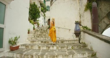 Amalfi kıyısındaki Atrani şehrindeki beyaz boyalı binalar arasında kadın dar taş merdivenlerden yukarı çıkıyor..