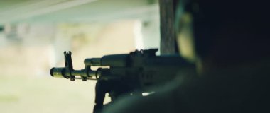 Nişancı, eğitim sırasında atış menzilinde dürbün kullanarak tüfekle nişan alıyor..