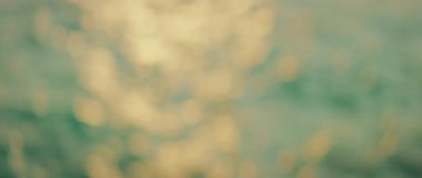 Deniz dalgaları ve hareket halindeki su yüzeyindeki Bokeh ışıkları üzerinde yumuşak, parlayan gün batımı.