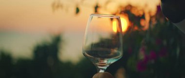 Sıcak yaz akşamlarında deniz manzaralı günbatımına karşı tutulan şarap kadehleri..