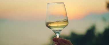 Gün batımında elinde şarap kadehiyle kıyı manzarasını seyrediyor..