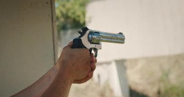 İki eli dışarıda hedef alınmış bir tabanca tutan kişi..